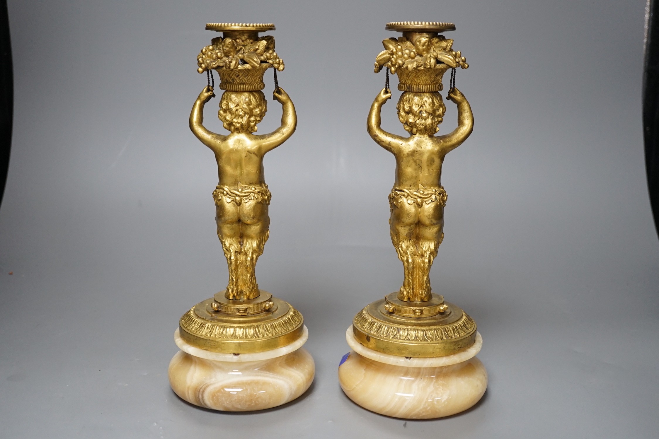 A pair of French gilt metal and onyx Bacchic faun candlesticks, 25.5 cms high